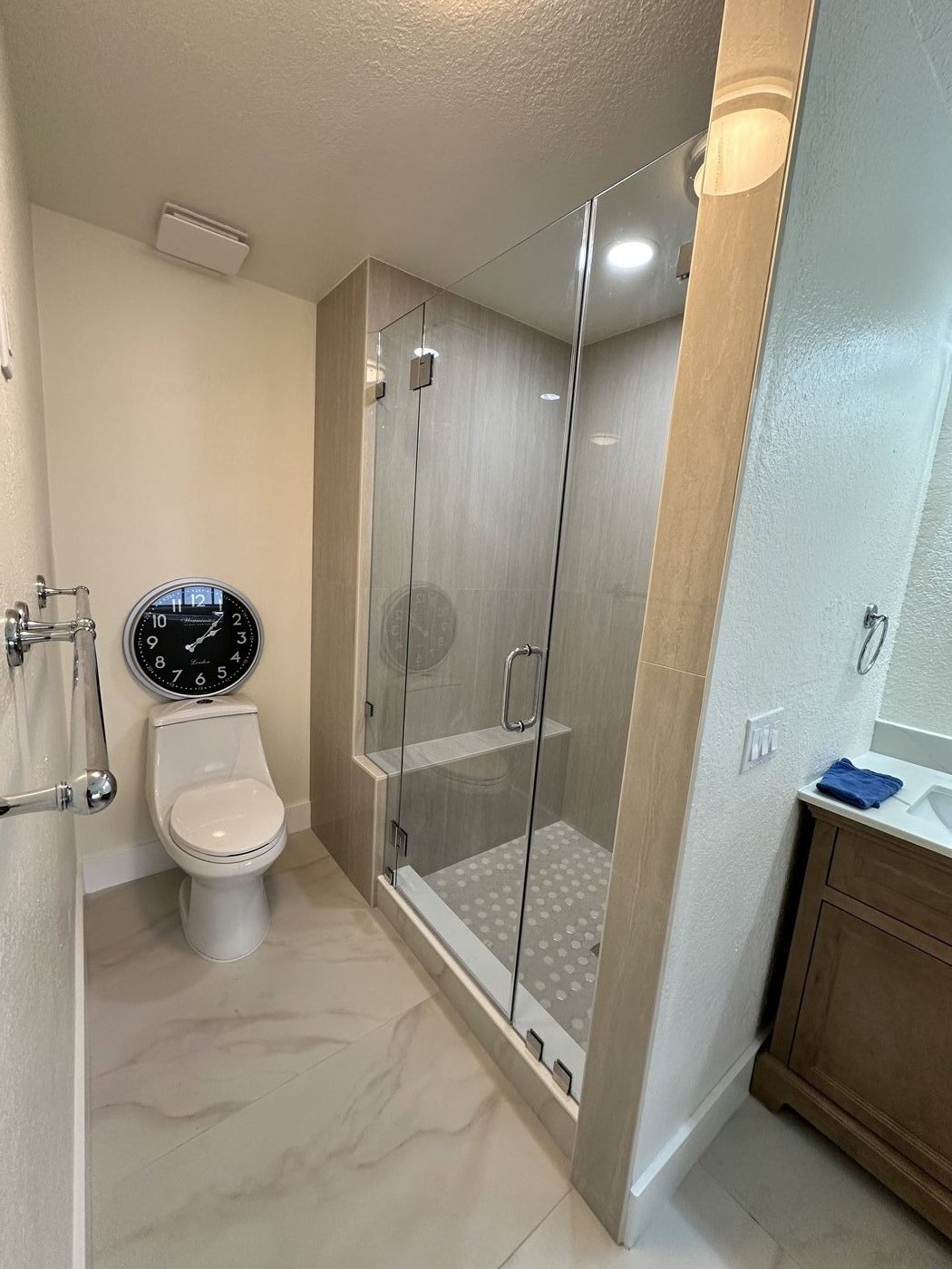Frameless glass shower with wood-grain tile back wall and matching wood vanity