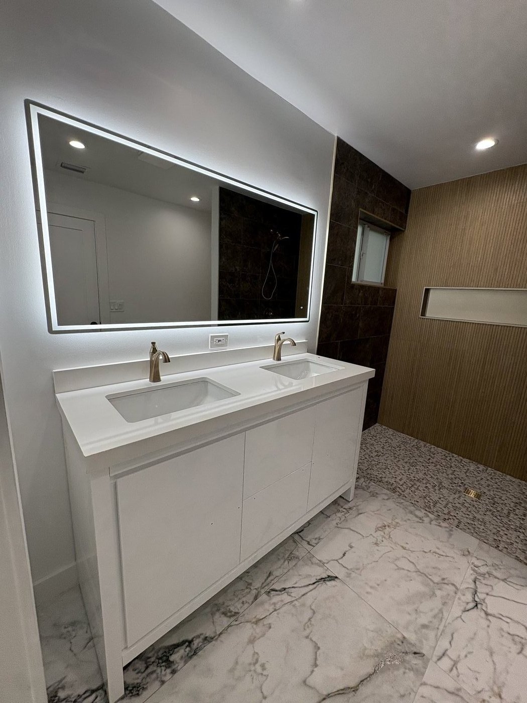 Double vanity with LED mirrors and marble feature wall