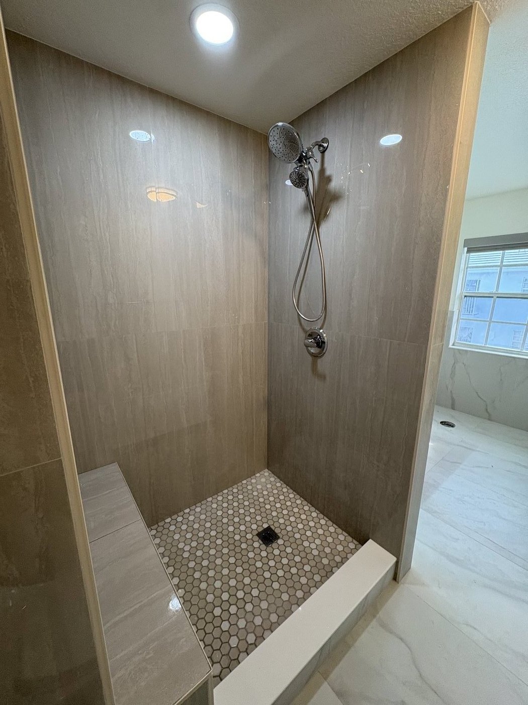 Walk-in shower with travertine tile, hexagon mosaic feature wall and brushed nickel fixtures