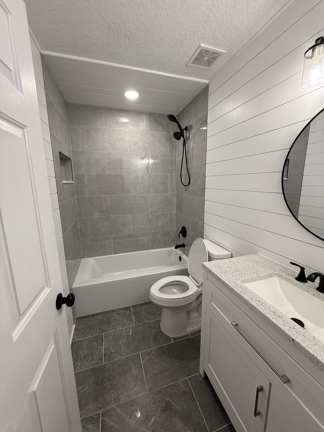 Black marble tub surround with niche and dark fixtures — Precision Builders & Design